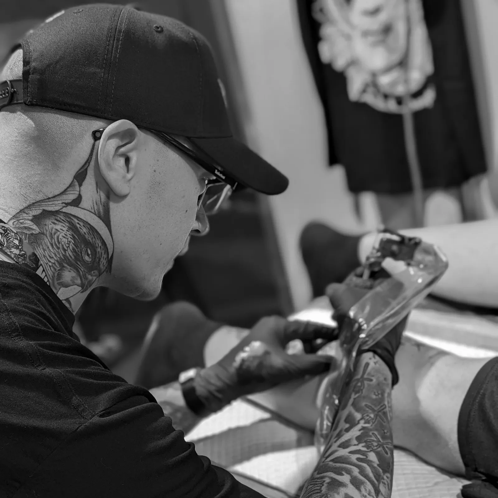 Joel Thongbai tattooing a client's leg